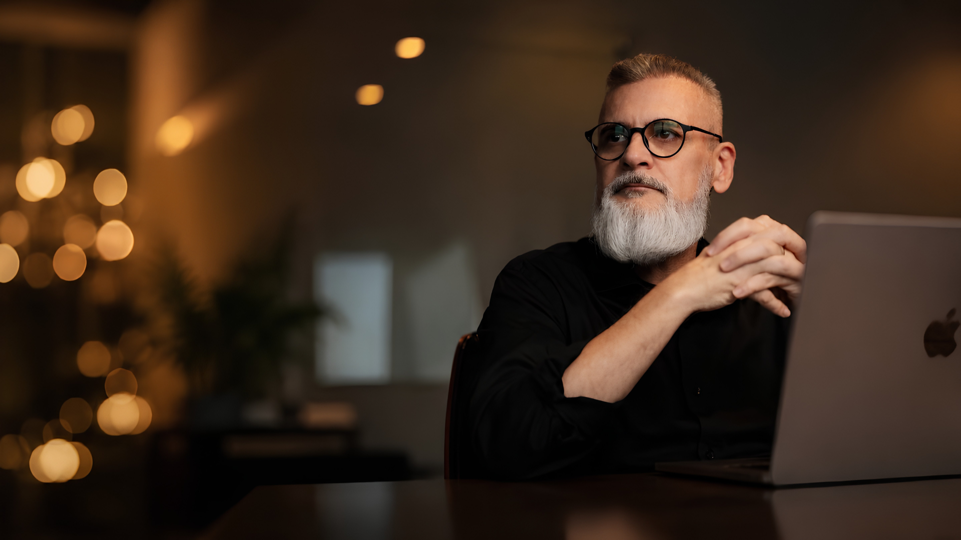 Alexandre Pscheidt sentado à mesa, de camisa preta, em ambiente com iluminação quente